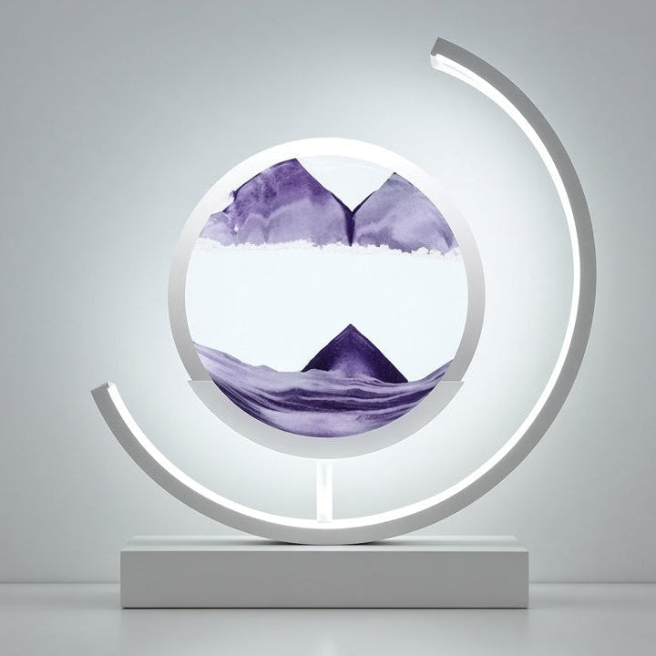 A modern circular LED light sculpture on a rectangular base, featuring a clear dome with purple watercolor mountain scenery inside, set against a minimalist gray background.