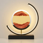 A modern LED arc lamp with a circular light box displaying a red and yellow landscape design, mounted on a black rectangular base.